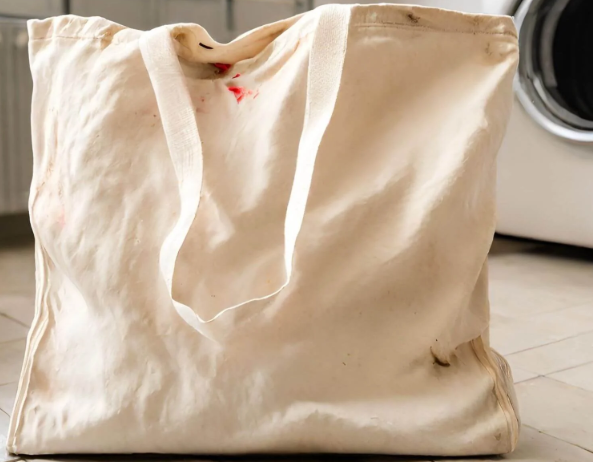 A white canvas bag featuring red stains, suggesting possible use or artistic design.