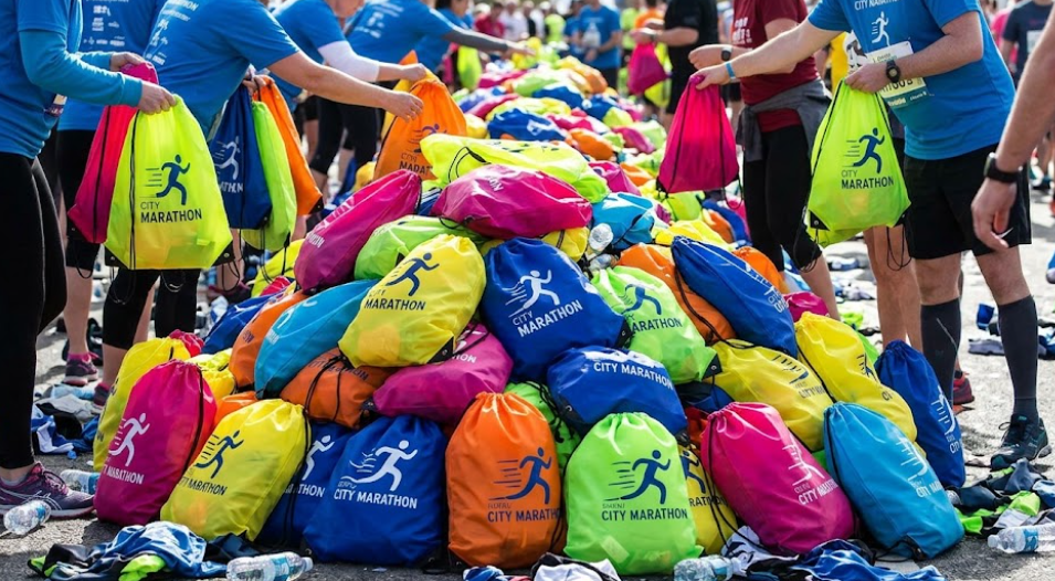 A Large Pile Of Vibrant Race Bags In Various Colors Stacked Together At An Outdoor Event